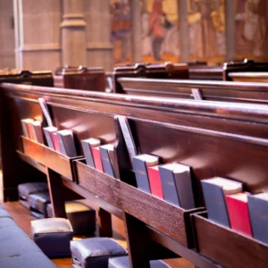 Church pews with hymnals and kneelers.